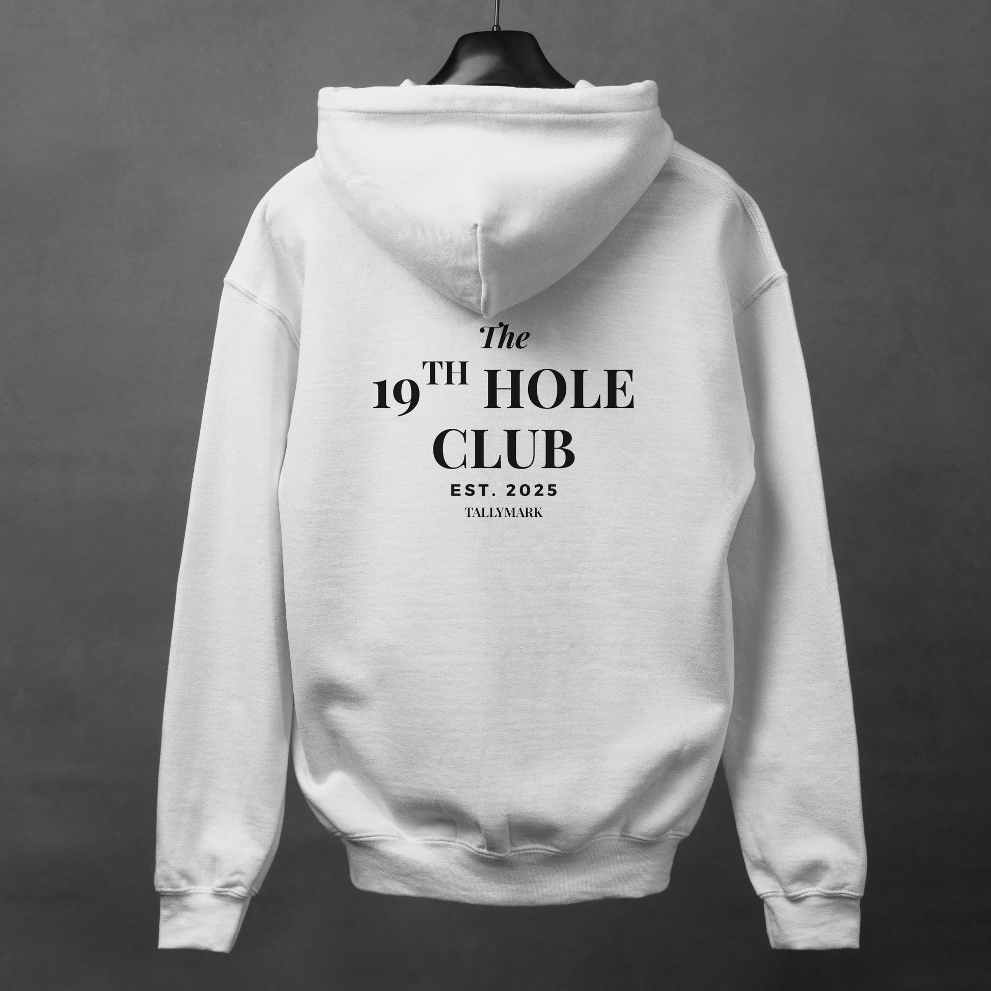 White hoodie with "The 19th Hole Club" text on the back against a dark background
