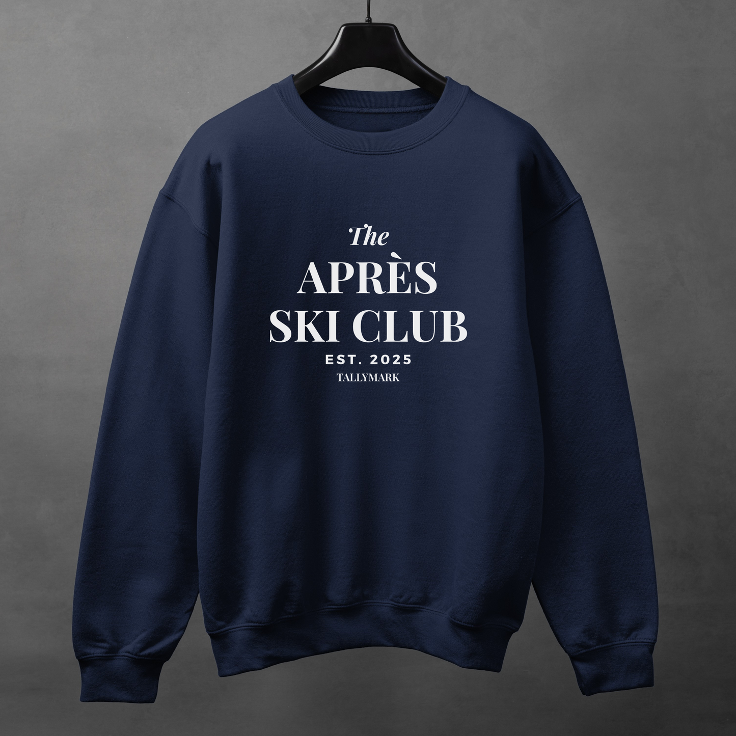Navy blue sweatshirt with 'The Après Ski Club' text on a gray background
