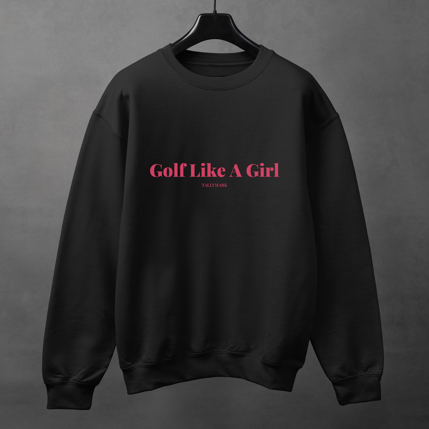 Black sweatshirt with pink 'Golf Like A Girl' text against a dark background