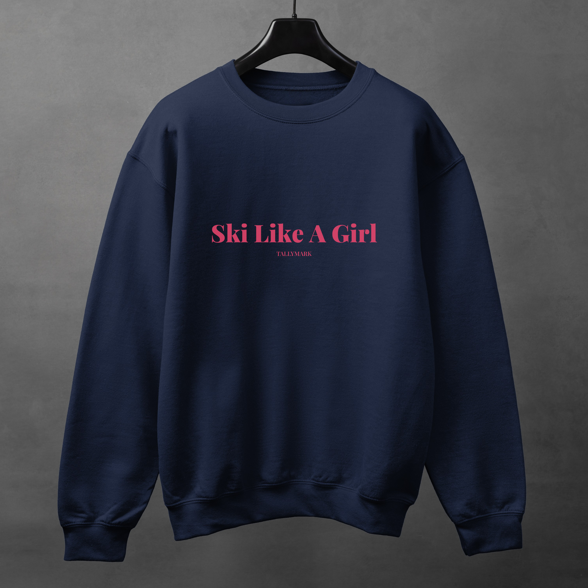 Navy blue sweatshirt with pink 'Ski Like A Girl' text against a dark background