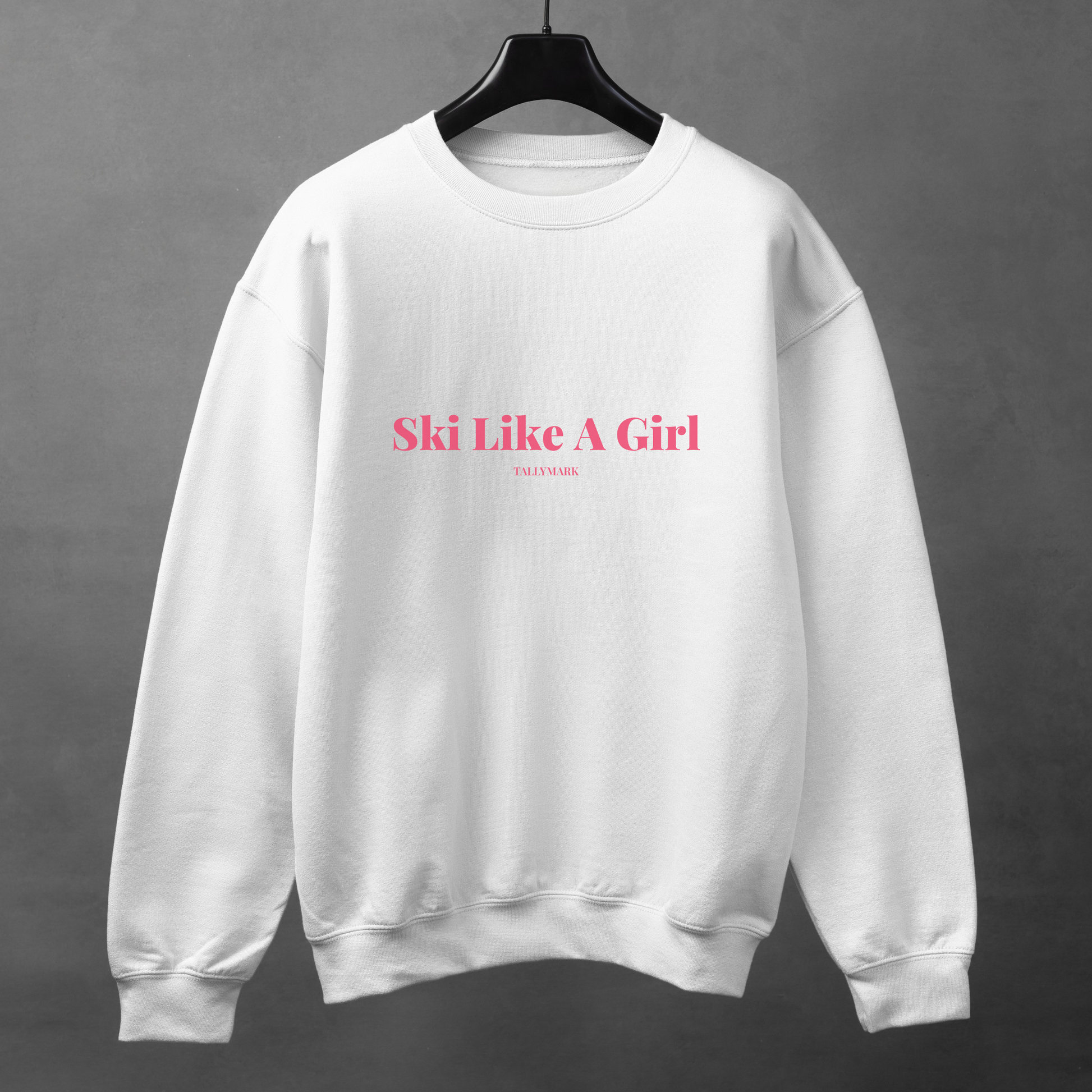 White sweatshirt with pink 'Ski Like A Girl' text against a dark background