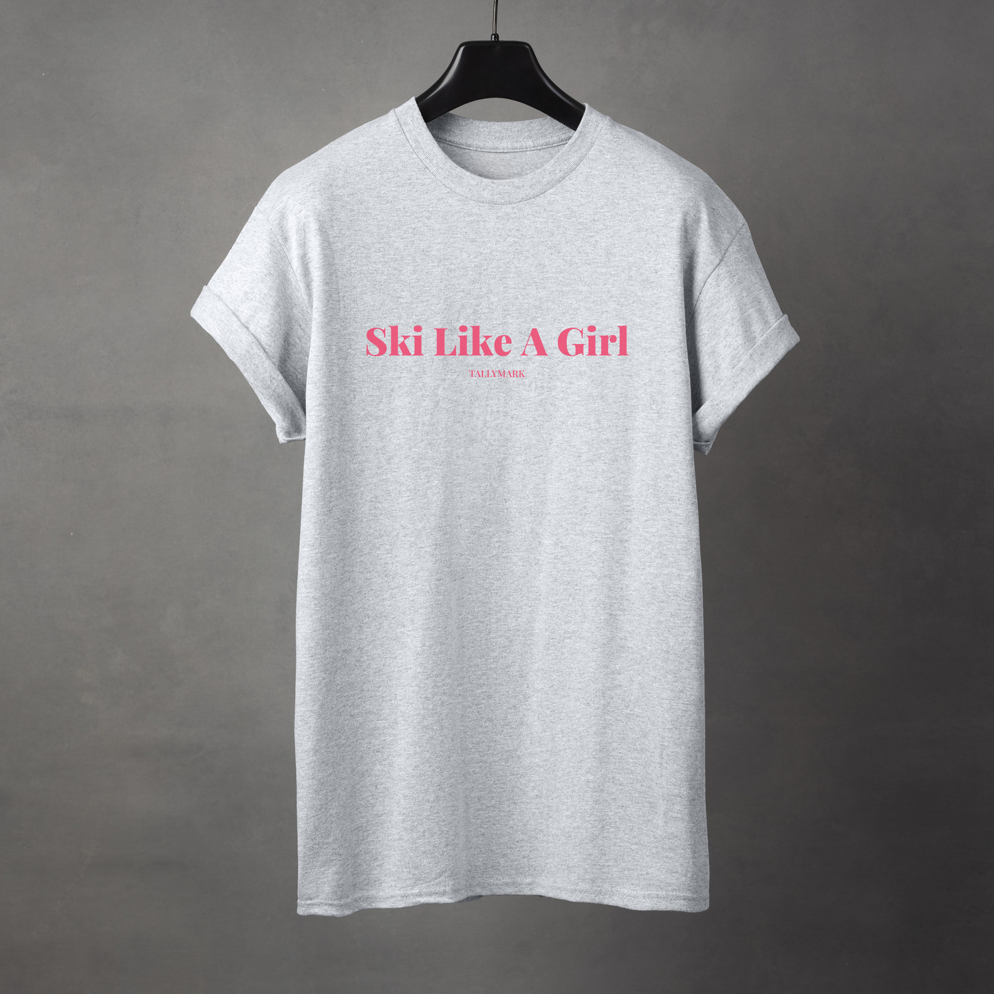 Gray t-shirt with pink 'Ski Like A Girl' text against a dark background
