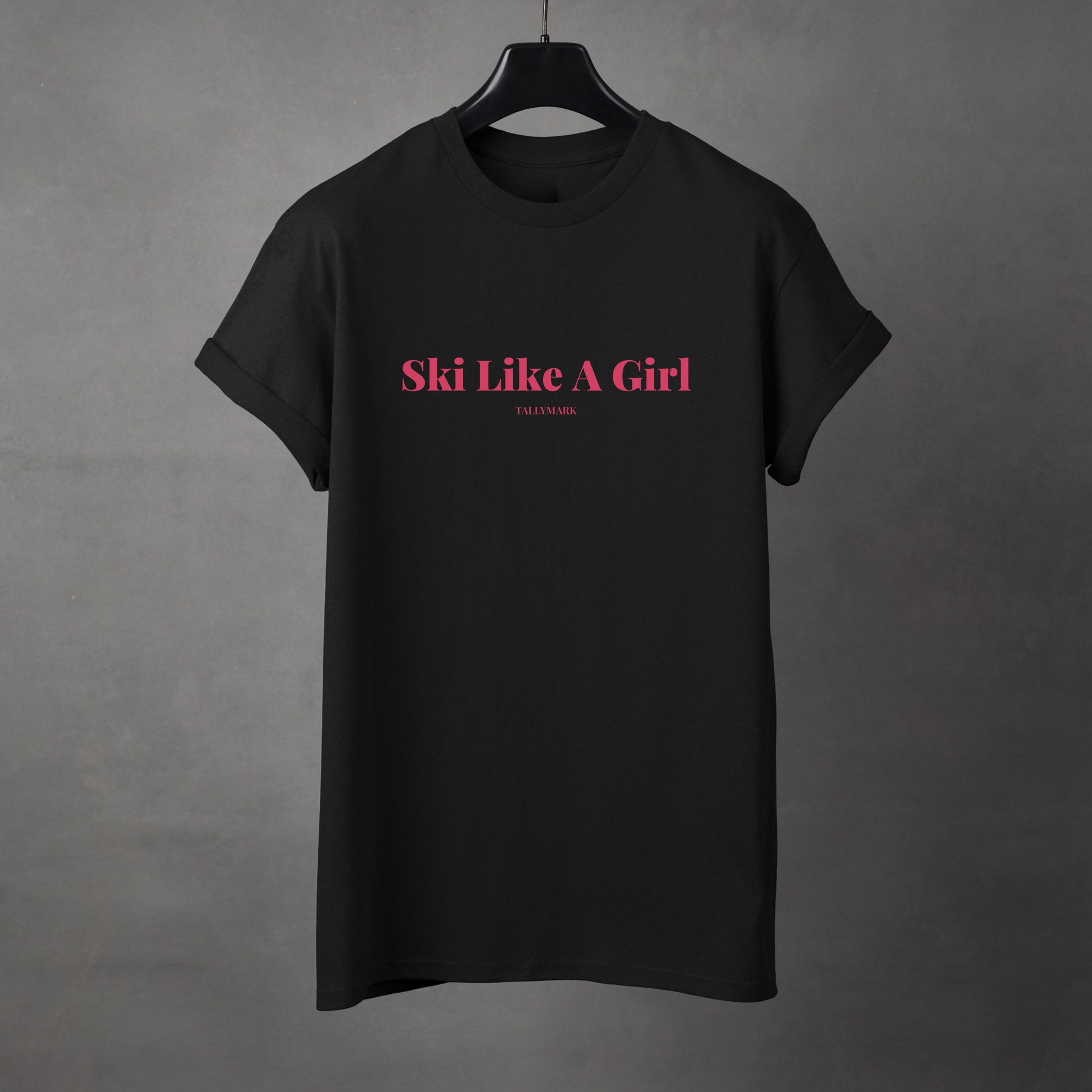 Black t-shirt with pink 'Ski Like A Girl' text against a dark background