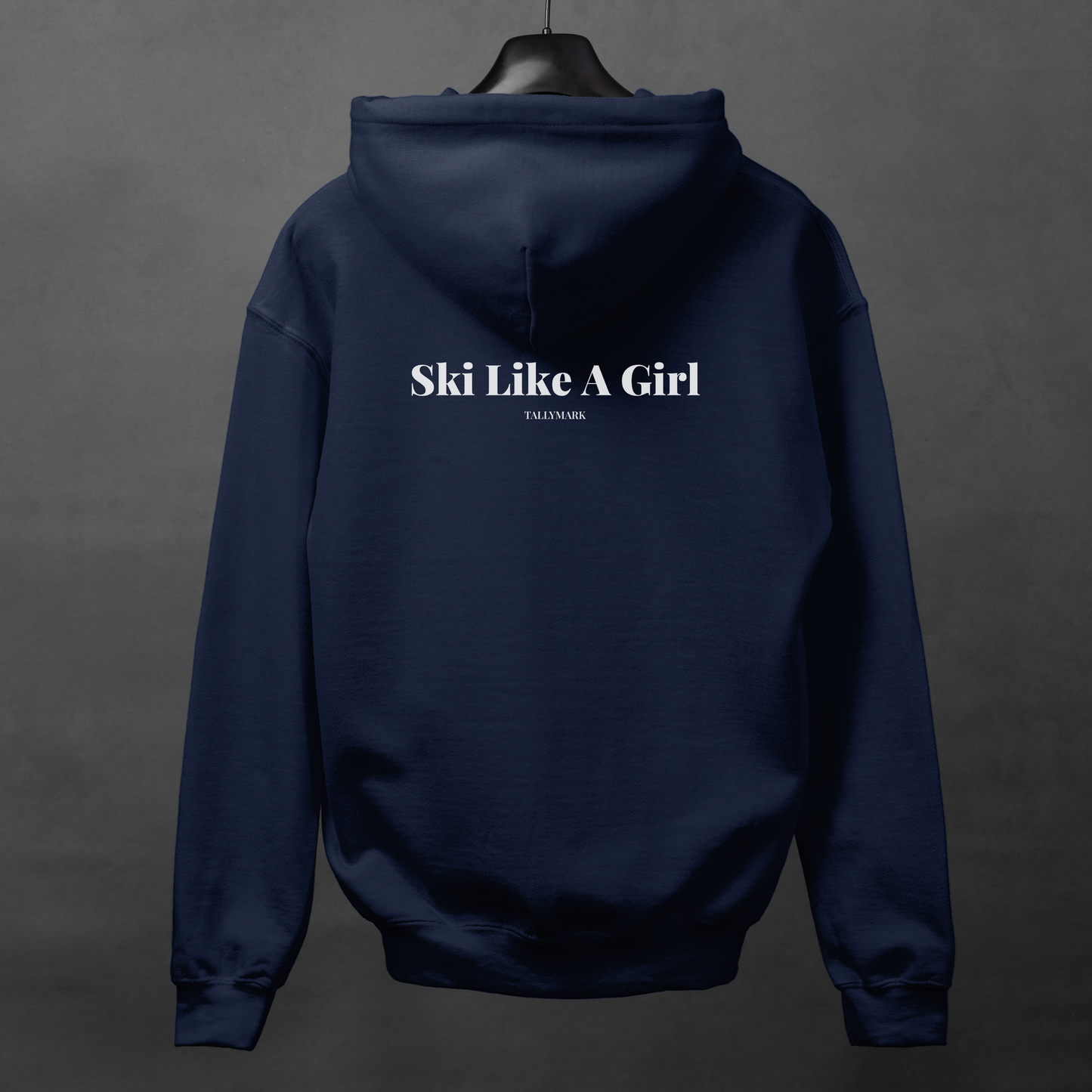 Navy blue hoodie with 'Ski Like A Girl' text on the back, displayed on a hanger against a dark background.