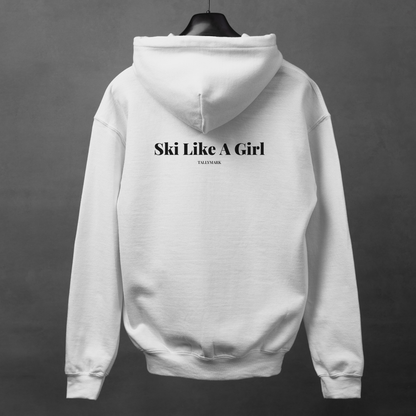 White hoodie with 'Ski Like A Girl' text on the back, displayed on a hanger against a dark background.